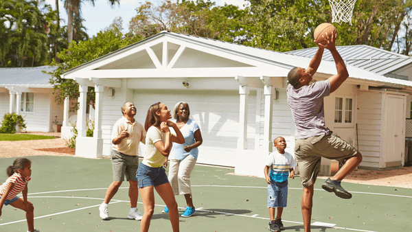 Family playing basketball in there backyard.