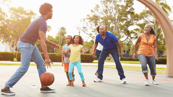 Family playing basketball at the park.