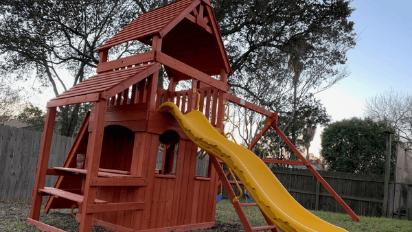 Backyard playset with lower level playhouse and wood roofs.