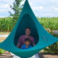 Two people inside a teal hanging pod with a cornfield in the background