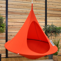 Orange hanging chair against a wooden wall with plants around