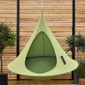 Green hanging pod chair against a wooden wall with plants.