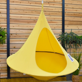 Yellow hanging chair against a wooden wall with plants around