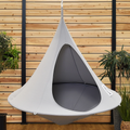 Gray hanging chair with 'Cacoon' branding against a wooden wall with plants.