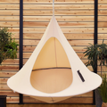Beige hanging chair against a wooden wall with plants