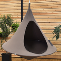 Gray hanging pod chair against a wooden wall with plants