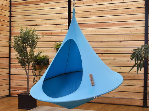 Blue hanging chair against a wooden wall with plants