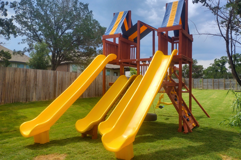 Colorful playground with yellow slides and a wooden structure on grass