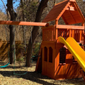 Wooden playground set with a yellow slide in a park setting