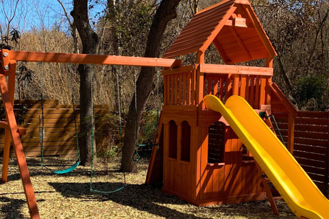 Wooden playground set with a yellow slide in a park setting