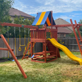 Children's playground set with a swing, slide, and climbing structure in a backyard.