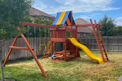 Children's playground set with a swing, slide, and climbing structure in a backyard.