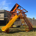Playset with yellow slide and climbing structure in a backyard
