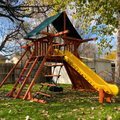 Wooden playground with a yellow slide in a backyard setting