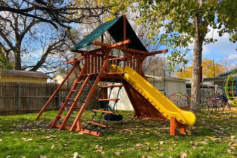 Wooden playground with a yellow slide in a backyard setting