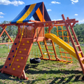 Colorful playground structure with slides and climbing wall in an outdoor setting.