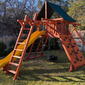 Wooden playground set with a yellow slide in a backyard