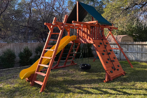 Wooden playground set with a yellow slide in a backyard