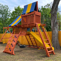 Colorful playground structure with slides and climbing elements in a backyard setting.