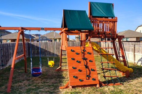 Wooden playground set with swings and slides in a backyard