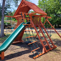 Wooden playground structure with a green slide in an outdoor setting