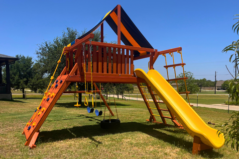 Colorful playground with a yellow slide and swings on a grassy area.