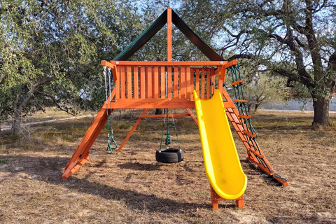 Children's playground set with a yellow slide and swings in an outdoor setting.