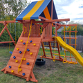 Colorful playground set with slides and climbing structures in a backyard setting.