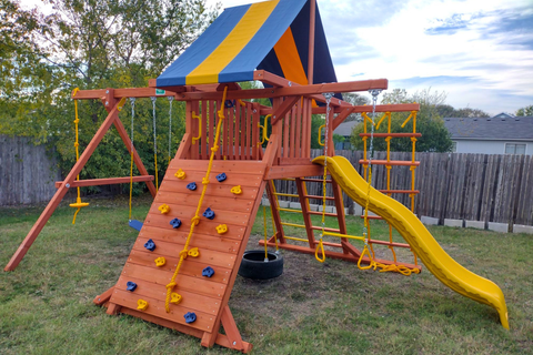 Colorful playground set with slides and climbing structures in a backyard setting.
