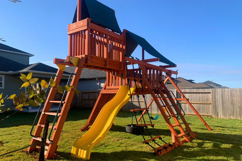 Wooden playground set with a yellow slide in a backyard