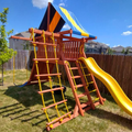 Colorful playground set with slides and ladders in a backyard.