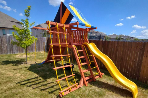 Colorful playground set with slides and ladders in a backyard.