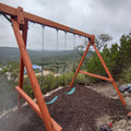 Wooden swing set with a scenic background of trees and mountains.