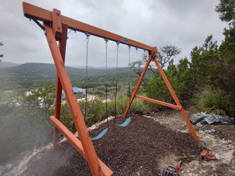 Wooden swing set with a scenic background of trees and mountains.