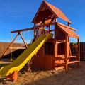 Wooden playground set with a yellow slide against a blue sky.