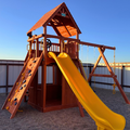 Wooden playground set with a yellow slide on a clear day
