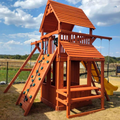 Wooden playset with slides and climbing wall in a backyard setting