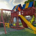Children's playground with a red play structure, yellow slide, and swings in a park setting.