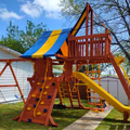 Colorful playground set with slides and climbing structures in a backyard.