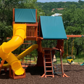 Children's playground with a yellow slide and blue roofs in a park setting.