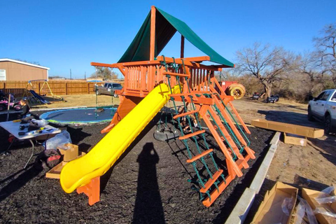 Children's playground with orange structure and yellow slide in an outdoor setting