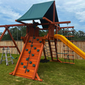 Children's playground with wooden climbing structure and yellow slide on grass