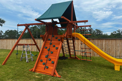 Children's playground with wooden climbing structure and yellow slide on grass