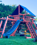 Green wooden playset with a slide in a backyard setting