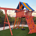 Children's playground with red swing set and climbing structure on a grassy area.